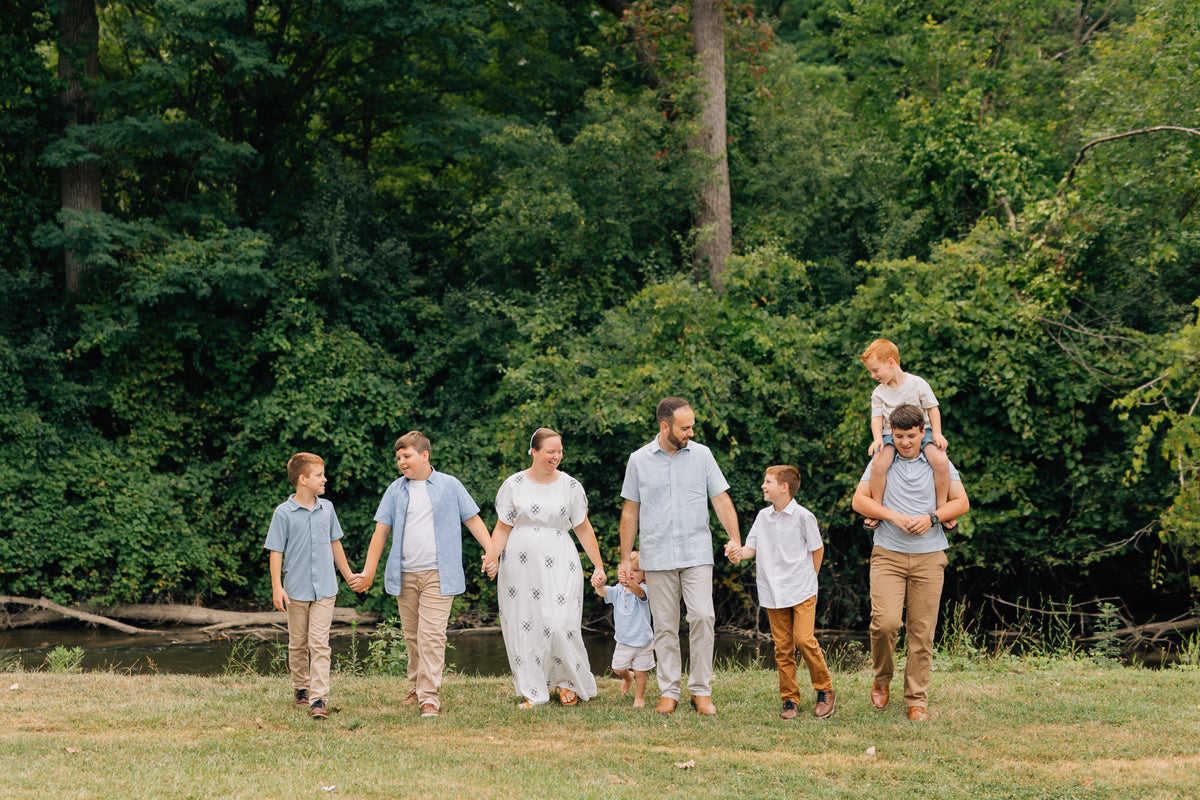 The Martin family walking hand in hand along the creek: Curt, Emily, and their six boys